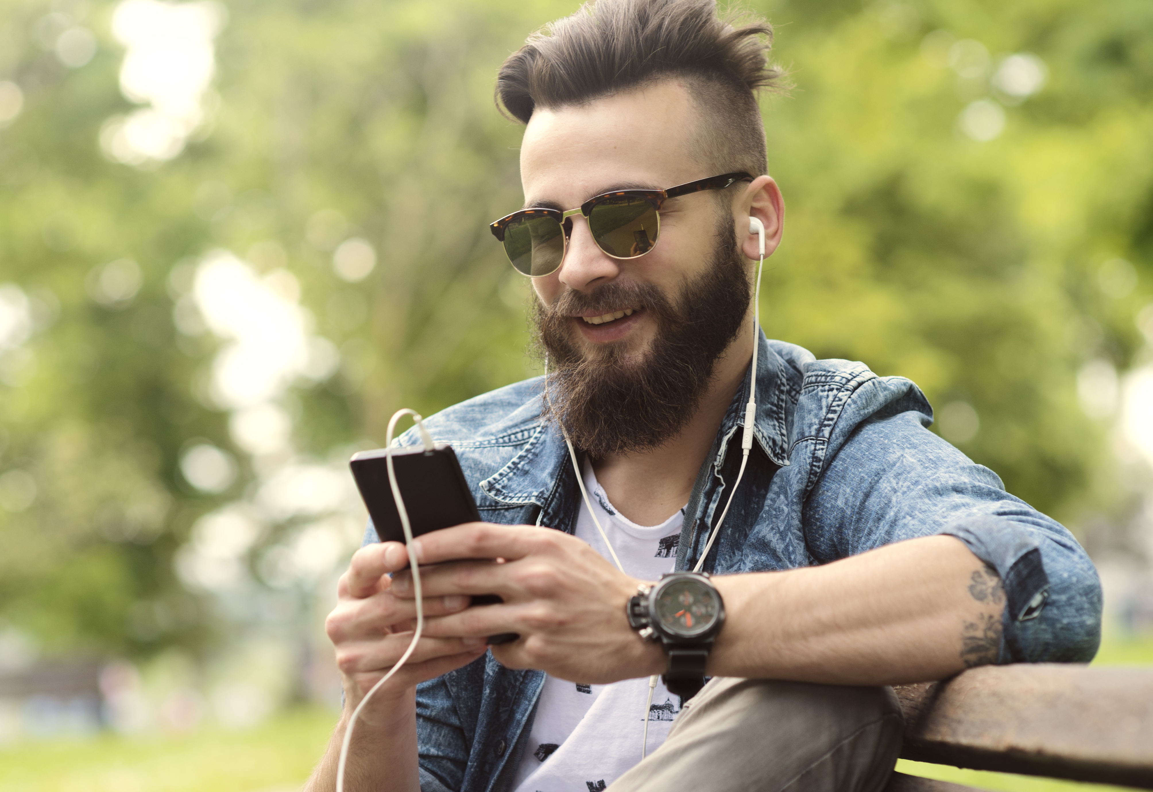 bearded young man on phone on park bench by LukaFunduk